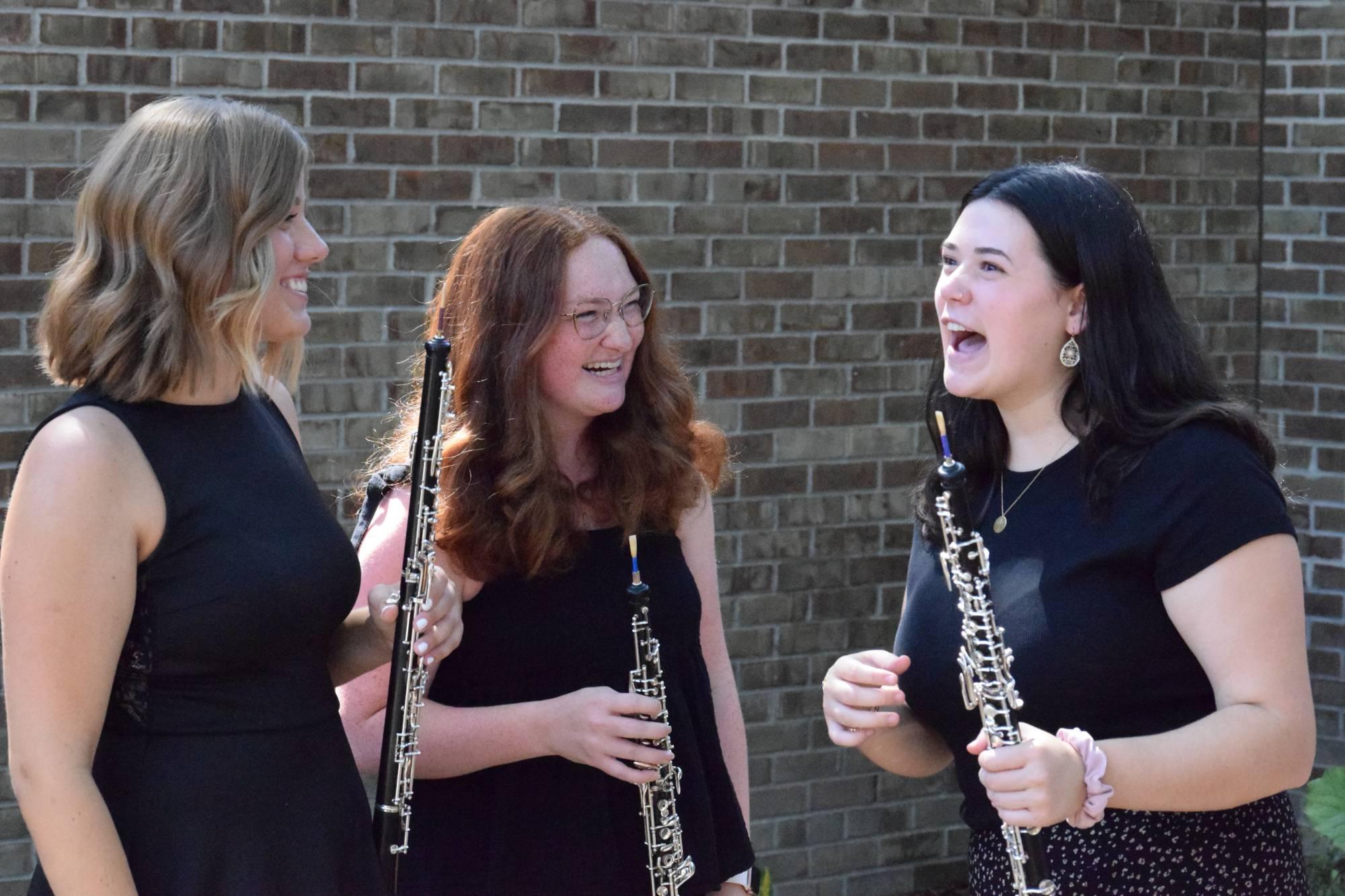 Lea Carter, Natalie Kline, and Natalie Feldpausch holding their oboes in the Marcia Haas garden at HCPA.